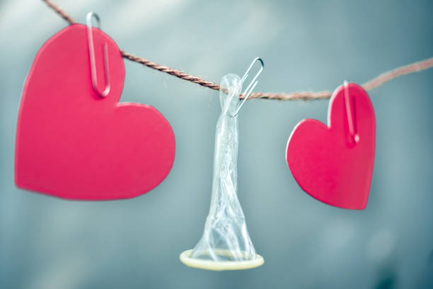 istock Close-Up Of Condom With Heart Shape Papers Hanging On String 932502900