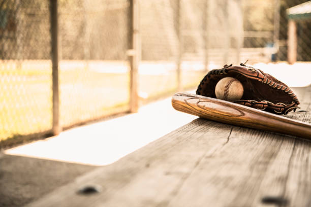 saison de baseball est ici.  bat, gant et boule sur le banc de l’étang-réservoir. - dugout baseball bench bat photos et images de collection