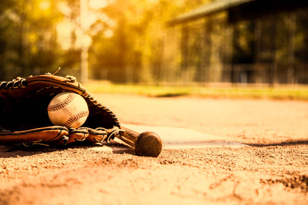 бейсбольный сезон здесь.  летучая мышь, перчатка и мяч на домашней тарелке. - baseball spring training baseballs sports glove стоковые фото и изображения