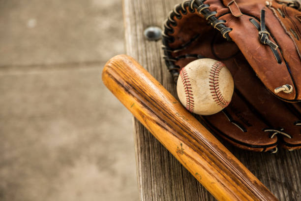 野球のシーズンはここにです。 バット、グローブ、ダッグアウトのベンチ上のボール。 - baseball bat 写真 ストックフォトと画像