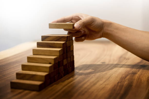 istock Cropped Hand Arranging Toy Blocks On Wooden Table 932534260