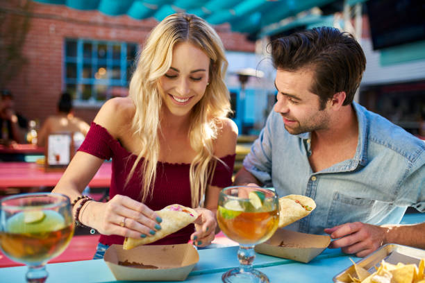 romantic couple eating street tacos at outdoor mexican restaurant - dating restaurant dinner couple imagens e fotografias de stock