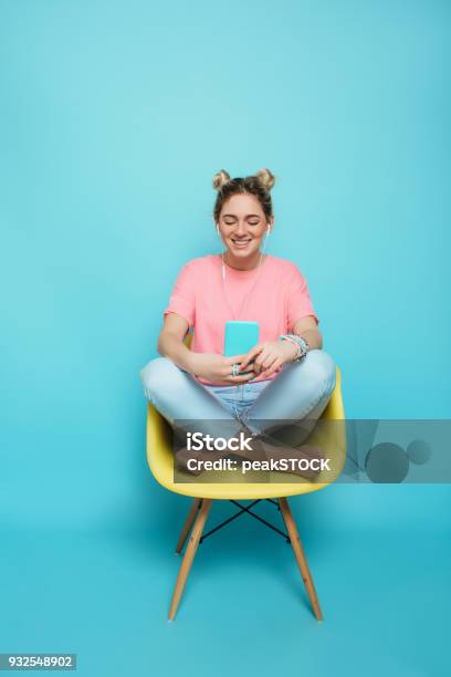 Photo libre de droit de Femme Assise Sur Une Chaise Avec Les Jambes Croisées Et Écouter De La Musique banque d'images et plus d'images libres de droit de Femmes