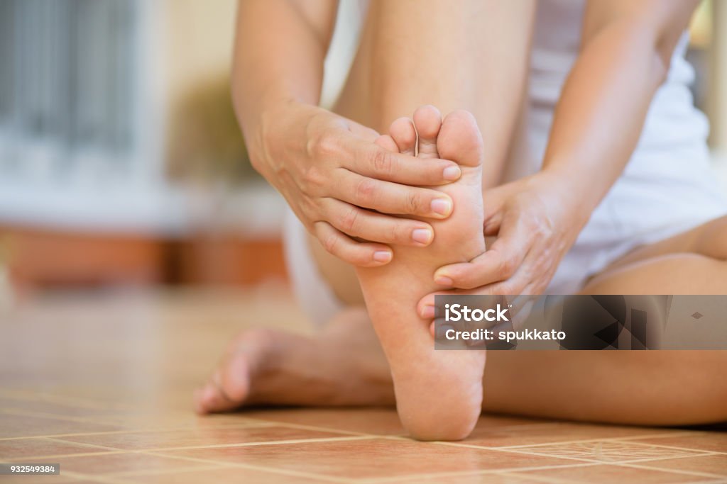 Closeup young woman feeling pain in her foot at home. Healthcare and medical concept. Foot Stock Photo