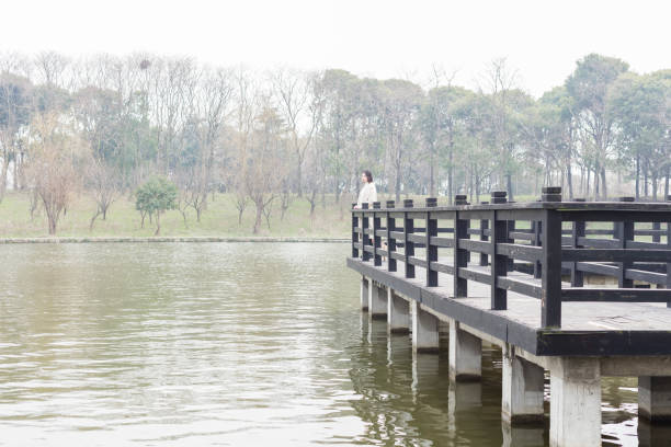 beautiful woman leaning on railing looking at view in park,China.