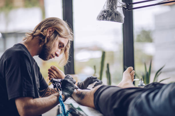 istock Artist making tattoo on man's leg in studio 932572164