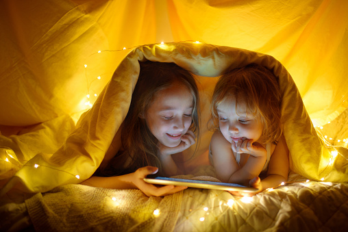 Dos niños con tablet pc bajo una manta en la noche. photo
