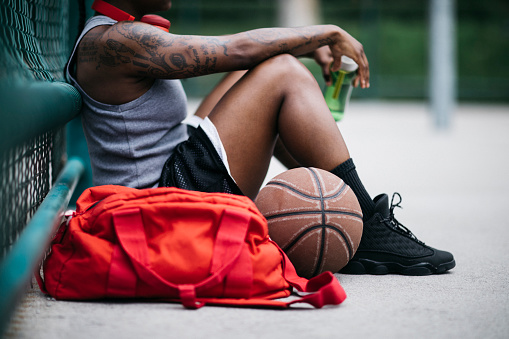 Girl sitting after basketball game surrounded by sports equipment