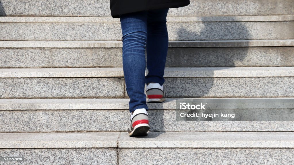 L’arrière de la jambe de la femme comme elle grimpe les escaliers. - Photo de Escalier libre de droits