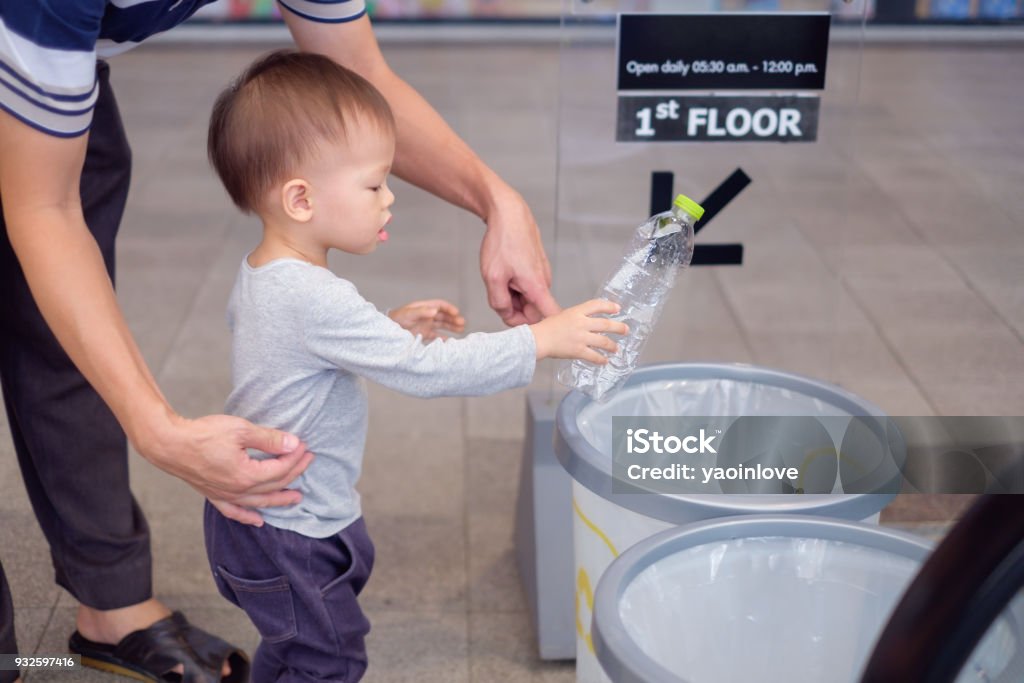 Asian father teach cute little 18 months, 1 year old toddler baby boy child throwing plastic bottle in recycling trash bin at public place Asian father teach cute little 18 months, 1 year old toddler baby boy child throwing plastic bottle in recycling trash bin at public place, Eco friendly Recycling Save the world & environment concept 2-3 Years Stock Photo