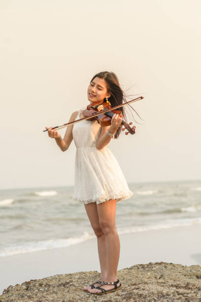 Happy woman playing violin on the beach.