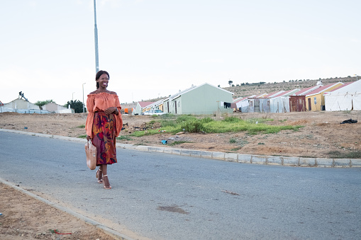 Full length portrait of a well dressed black woman walking to work with her work bag, Kayamandi - Cape Town