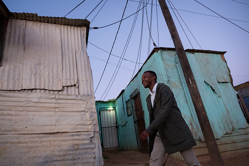 A confident young black businessman walks through the streets of the township early in the morning on his way to work, Kayamandi Cape Town