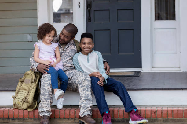 Army dad talks with his kids before his deployment African American Army dad sits on the porch with his preteen son and preschool age daughter before he leaves for an overseas assignment. camouflage clothing photos stock pictures, royalty-free photos & images