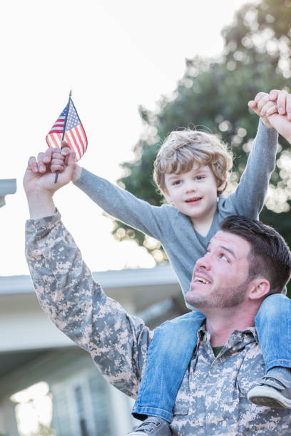 istock Little boy sitting on army dad's shoulders 932608628