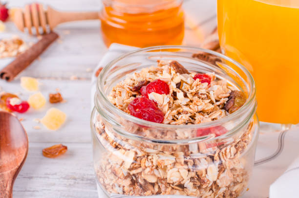 Healthy Breakfast of homemade Granola in glass jar and spoon on old rustic white background
