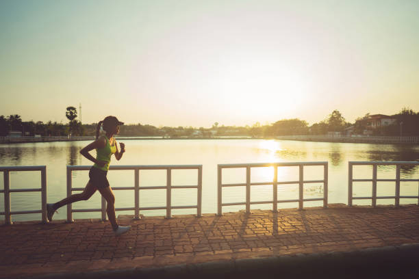 アジアの女性は、公園でジョギングします。午前中に - scoring run ストックフォトと画像