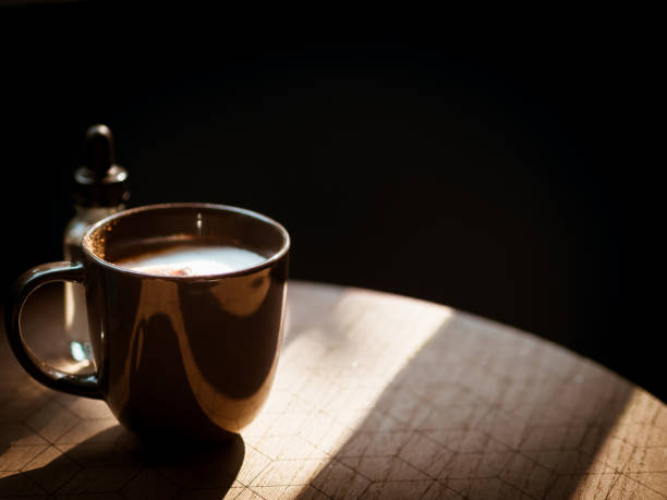 istock Black cup of coffee in morning light from window. 932616262