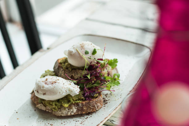 istock Avocado with poached eggs on toast in trendy hipster restaurant high end 932623762