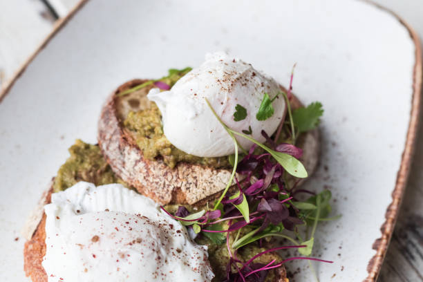 istock Avocado with poached eggs on toast in trendy hipster restaurant high end 932623958