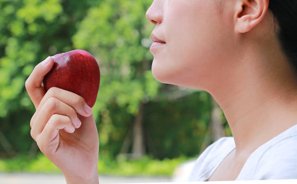 istock Side view of young asian girl eats an apple. 932624154