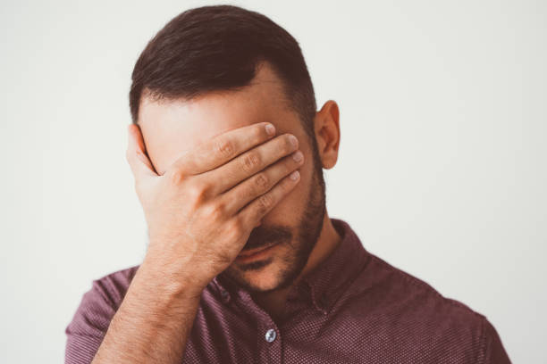 istock Young Man Covering Eyes with Hand 932624558