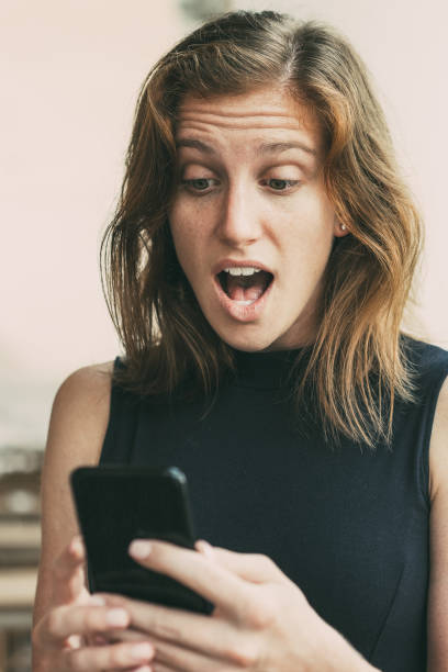 istock Surprised Young Woman Using Smartphone Outdoors 932627360