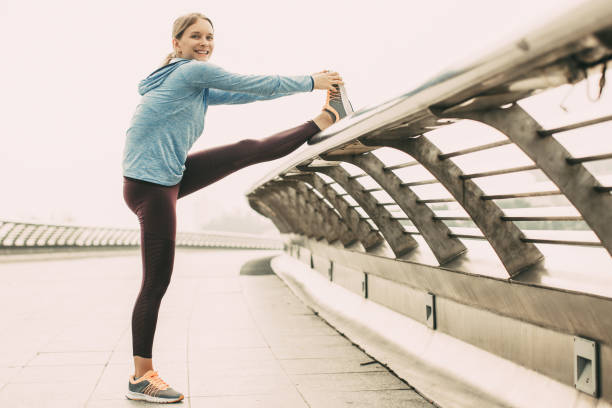istock Smiling Sporty Woman Stretching Leg on Bridge 932637288