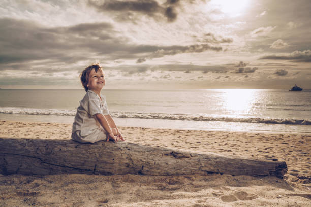 istock Cute happy boy enjoying on the beach at sunset. 932637354