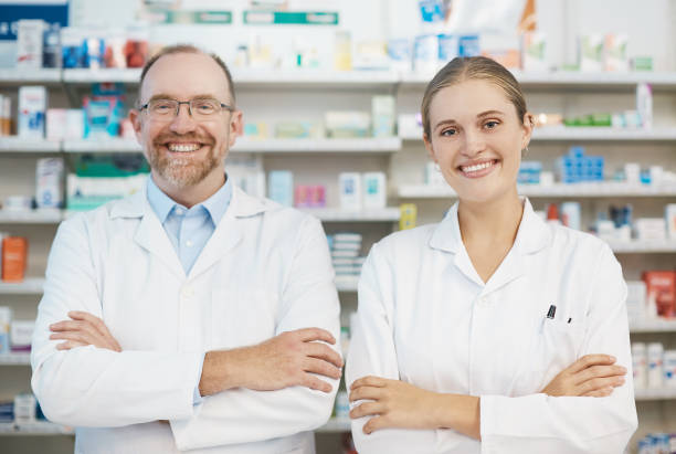 istock Senior and junior pharmacists stand behind dispensary counter smiling confidently 932639492
