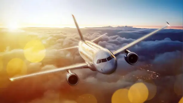 Airplane traveling above a scenic cloudscape. The sun is standing low just above the horizon. Colorful image with a lot of atmosphere.