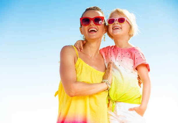 istock smiling mother and daughter on seashore looking into distance 932661660
