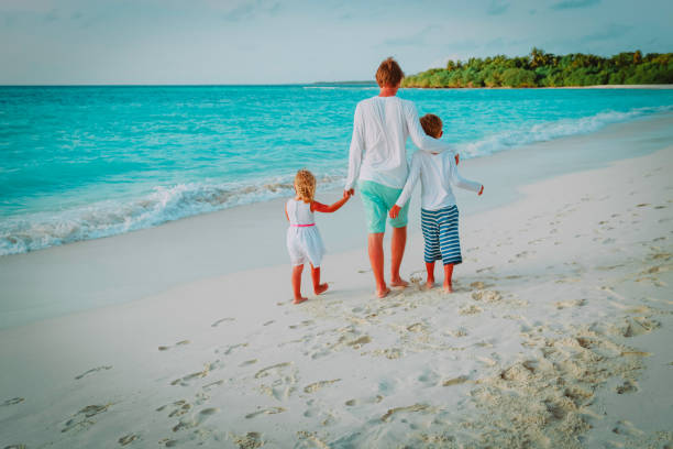 istock father and two kids walking on beach 932668994