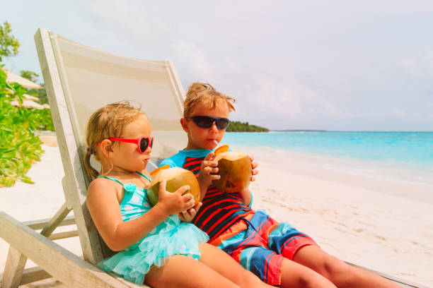 istock little boy and girl drinking coconut on beach 932669686