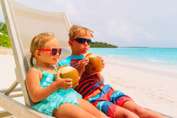 istock little boy and girl drinking coconut on beach 932669794