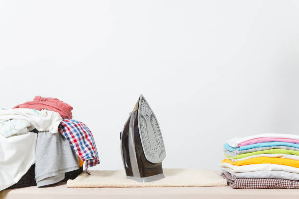 gros plan fer à vapeur, repassage des vêtements colorés, lavées linge, vêtements familial sur planche à repasser isolé sur fond blanc. concept de ménage. copiez l’espace pour la publicité. avec la place pour le texte. - iron table photos et images de collection