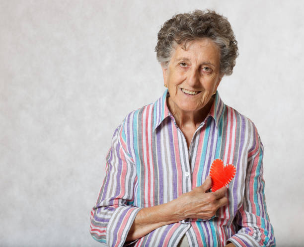 старшая женщина держит сердце в руках. - respect women human teeth people стоковые фото и изображения