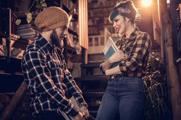 istock Happy college couple talking on staircase in the library. 932679434