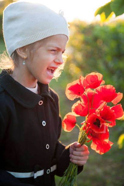 кричать маленькая кавказская девушка в шляпе и пальто с букетом маков в руках весной - red poppies audio стоковые фото и изображения
