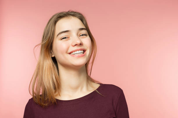 frau, lächeln mit perfekten lächeln und weiße zähne auf die rosa studio-hintergrund und blick in die kamera - youth culture women human face portrait stock-fotos und bilder