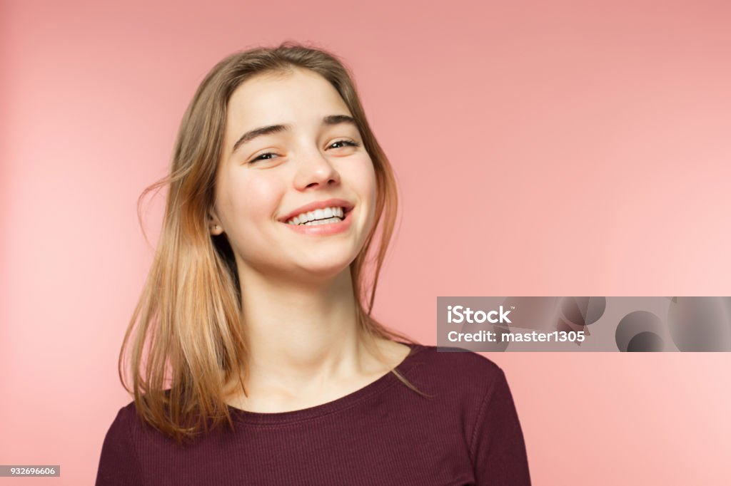 Mulher sorrindo com sorriso perfeito e dentes brancos sobre o fundo rosa estúdio e olhando para a câmera - Foto de stock de Adolescente royalty-free
