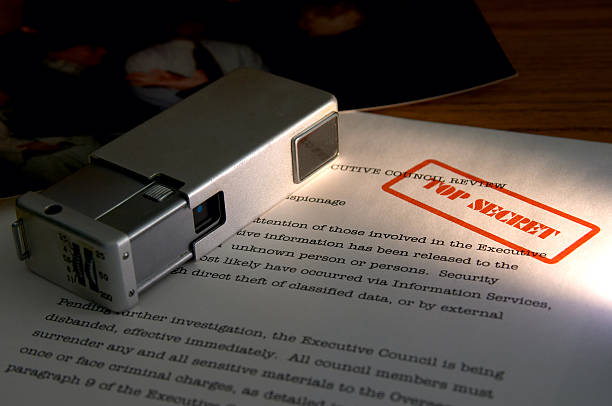 A spy camera sitting on top of top secret documents Mini camera and secret documents (photo in upper left is one of my own and contains no recognizable images) logistical stock pictures, royalty-free photos & images