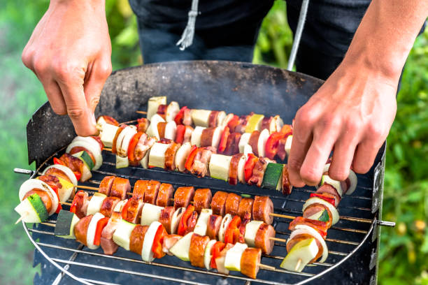グリル料理夏の庭園でのバーベキュー グリルで野菜や肉の串焼き、バーベキュー芝生の上で野外パーティーを準備する調理者の手 - barbecue grill broiling barbecue vegetable ストックフォトと画像
