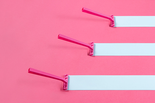 Conceptual still life with razor on pink geometrical background.