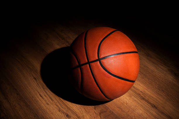 Basketball sitting in the spotlight on a court Basketball sitting in the spotlight on a court college basketball court stock pictures, royalty-free photos & images