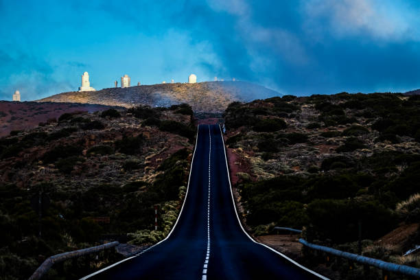 Long road to observatory park in Tenerife Colored season outdoor in mountain with curved road to travel and explore. asphalt and white lines to go to El Teide vulcan in Tenerife observatory park observatory tenerife canary islands el teide national park stock pictures, royalty-free photos & images