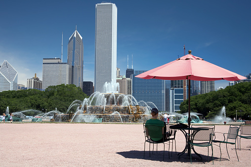 Girl sitting in the shade of a cafe umbrella near Chicago's Buckingham fountain