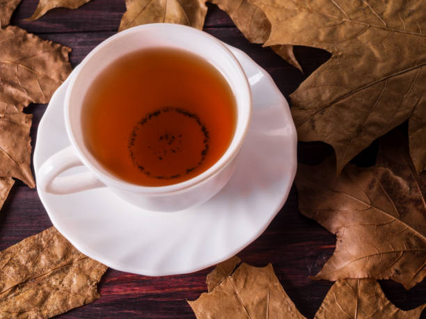 istock White cup with green tea on a wooden table with autumn leaves 932725130