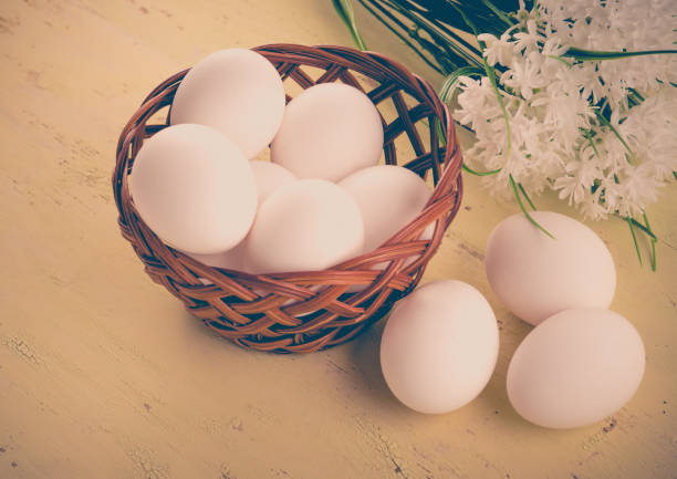 huevos frescos en una cesta y sobre una mesa de madera. - animal egg eggs basket yellow fotografías e imágenes de stock