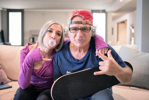 Young at heart grandparents: Rock and roll sign with skateboard and bubble gum